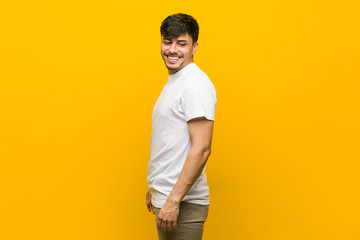 Young hispanic casual man looks aside smiling, cheerful and pleasant.