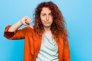 Young redhead elegant woman showing a dislike gesture, thumbs down. Disagreement concept.