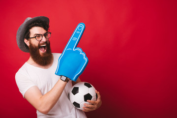 Photo of bearded supporter, with big finger glove, holding soccer ball