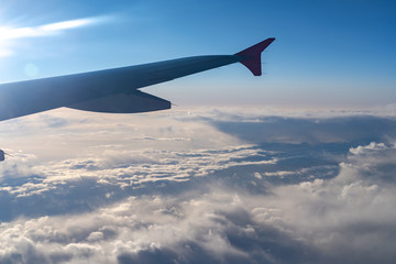 Fototapeta premium Up in the air, view of aircraft wing silhouette with dark blue sky horizon and cloud background in sun rise time, viewed from airplane window