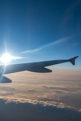 Fototapeta premium Up in the air, view of aircraft wing silhouette with dark blue sky horizon and cloud background in sun rise time, viewed from airplane window