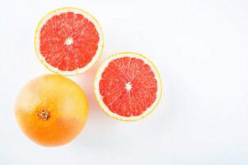 Fresh grapefruit and cut red flesh on white background