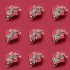 Red giftbox with silver ribbon on red surface. Top view. Seamless pattern.