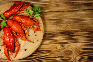 Boiled crayfish on cutting board on wooden table. Top view