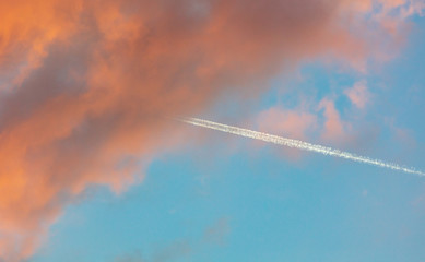 Trail from the plane in the sky at sunset