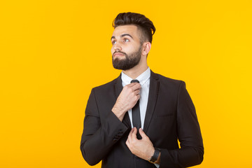 Charming young self-confident businessman wearing formal clothes posing on a yellow background. Concept of business and success.
