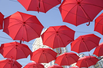  Red umbrellas against the blue sky and the bright building. Abstract background with umbrellas