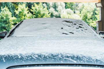 selective focus of modern grey car with white foam in car wash