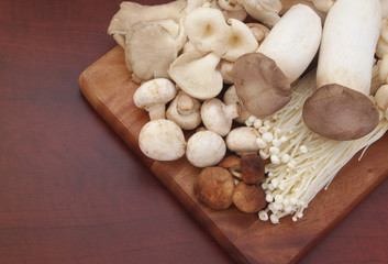 Assorted mushrooms on cutting board on brown table