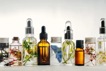 Fotobehang Transparent Bottles of essential oil with fresh herbs. © saquizeta