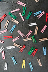Hand made background, lot of colorful wooden clothespins on dark gray concrete, copy space