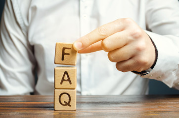 Businessman puts wooden blocks with the word FAQ (frequently asked questions). Collection of frequently asked questions on any topic and answers to them. Instructions and rules on Internet sites - obrazy, fototapety, plakaty