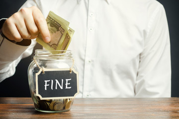 A man puts dollars in a glass jar with the word Fine. Saving money and paying a fine. Punishment...