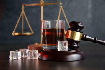 The concept of a DUI. Law hammer, alcohol and car keys on wooden table, dark background