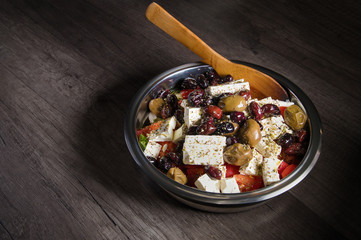 Close-up of delicious gourmet tomato and olives feta cheese salad sprinkled with herbs spices in a metal bowl. The concept of delicious and healthy vegetarian food and body detoxification