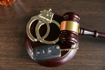 The concept of a DUI. Law hammer, alcohol and car keys on wooden table, dark background