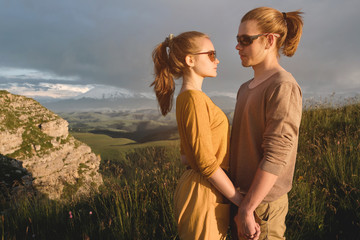 Portrait of a romantic young couple in nature. A man and a girl in sunglasses look at each other with loving looks on the track. The concept of a young family and heterosexual relationships