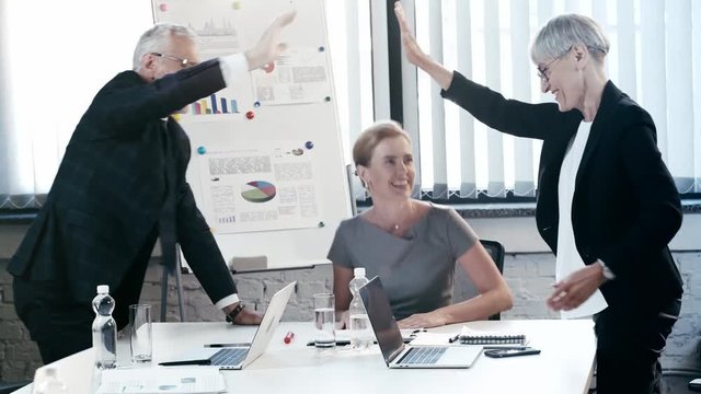 happy businesswomen and businessman giving high five in office 