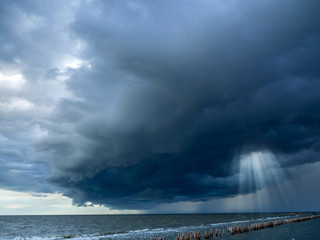 Sun beam in dark clouds and sky before thunderstorm at the seashore, Monsoon season, Natural backgrounds: stormy sky