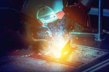 Industrial welder worker is welding metal part in factory with protective mask welding metal 