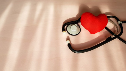 Stethoscope and red heart on natural light sources background, top view. Healthcare and medical concept.