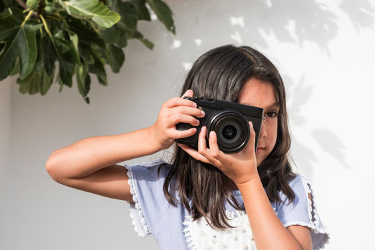 six year old girl with camera taking pictures and posing