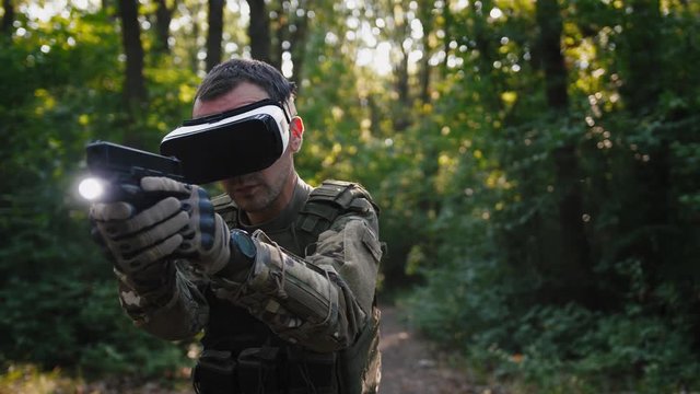 Soldier aiming with gun wearing virtual reality glasses outdoors