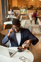 Afro-american working at the laptop and pouring himself tea.