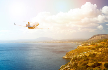 business jet flies over the beach resort area, the sky with clouds and yellow rays of sun
