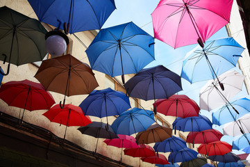 Fototapeta na wymiar colorful umbrellas against the sky between the houses, beautiful umbrellas
