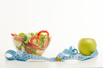Healthy foods layered on white backgroud with a measuring tape nearby.