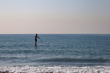 Silhouette of a man doing paddle surf