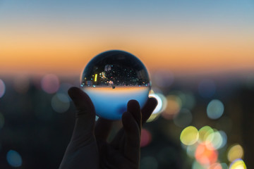 Crystal glass ball during sunset on a cityscape with bokeh