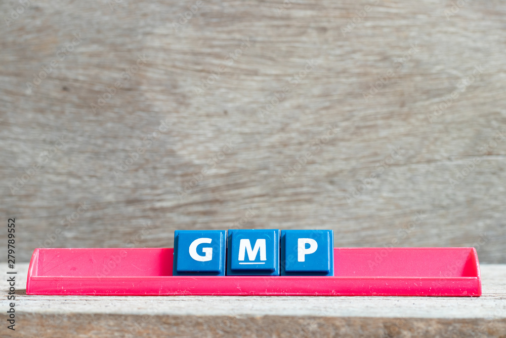 Sticker Tile letter on red rack in word GMP (Abbreviation of good manufacturing practice) on wood background