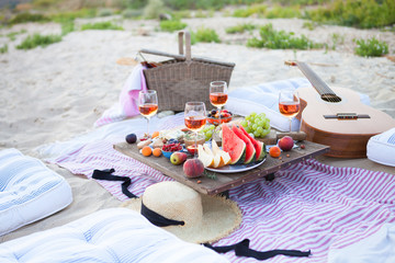 Picnic on the beach at sunset in the style of boho, food and drink conception