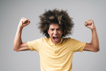 Photo of ecstatic caucasian man with afro hairstyle screaming and raising arms