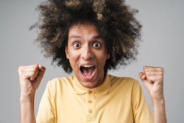 Photo of emotional caucasian man with afro hairstyle screaming and clenching fists