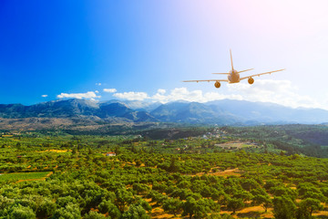 rear view plane flying over beautiful valley , mountains, clouds and sun on background