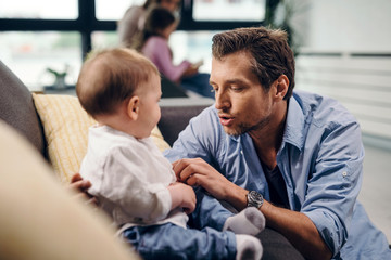 Mid adult father talking to his baby son in the living room.