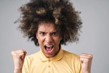 Photo of excited caucasian man with afro hairstyle screaming and clenching fists