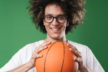 Portrait closeup of young happy man with afro hairstyle holding basketball and looking at camera