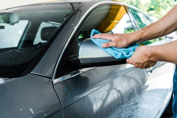 Foto op Canvas cropped view of man cleaning wet car mirror with blue rag © LIGHTFIELD STUDIOS