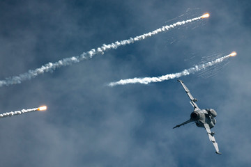 Modern jet fighter shooting flares with sparks during display 