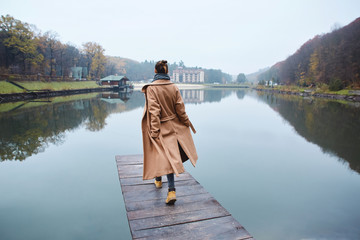 Woman walking on the wooden pier in the park at autumn.