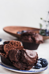 Chocolate muffins on wooden cutting board, halved, close up