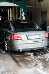modern grey vehicle with white foam on floor in car wash