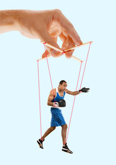 Man like a puppet in somebodies hands on blue background. Concept of unfair manipulation, phycology...