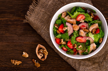 fresh Chicken salad with strawberries on a dark wooden background