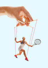Woman like a puppet in somebodies hands on blue background. Concept of unfair manipulation,...