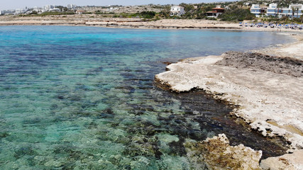 Fototapeta na wymiar The rocky coast of Cyprus with azure water near Ayia Napa. Flying drone over the sea